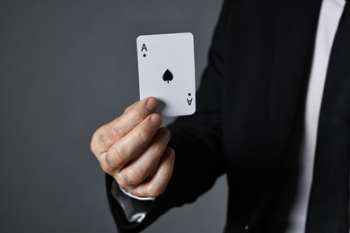 Photo of Illusionist with playing card on grey background, closeup