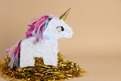 Photo of Unicorn shaped pinata and party decor on beige background, space for text