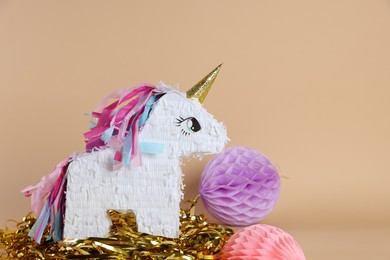 Photo of Unicorn shaped pinata and party decor on beige background, space for text