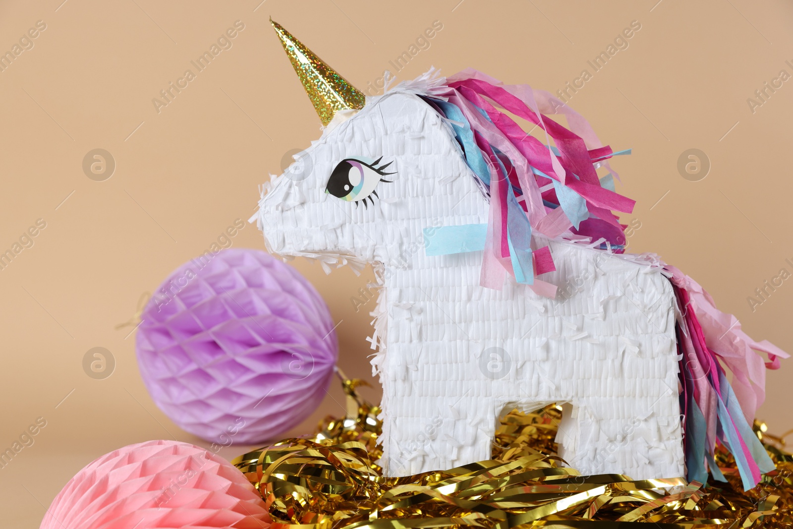 Photo of Unicorn shaped pinata and party decor on beige background