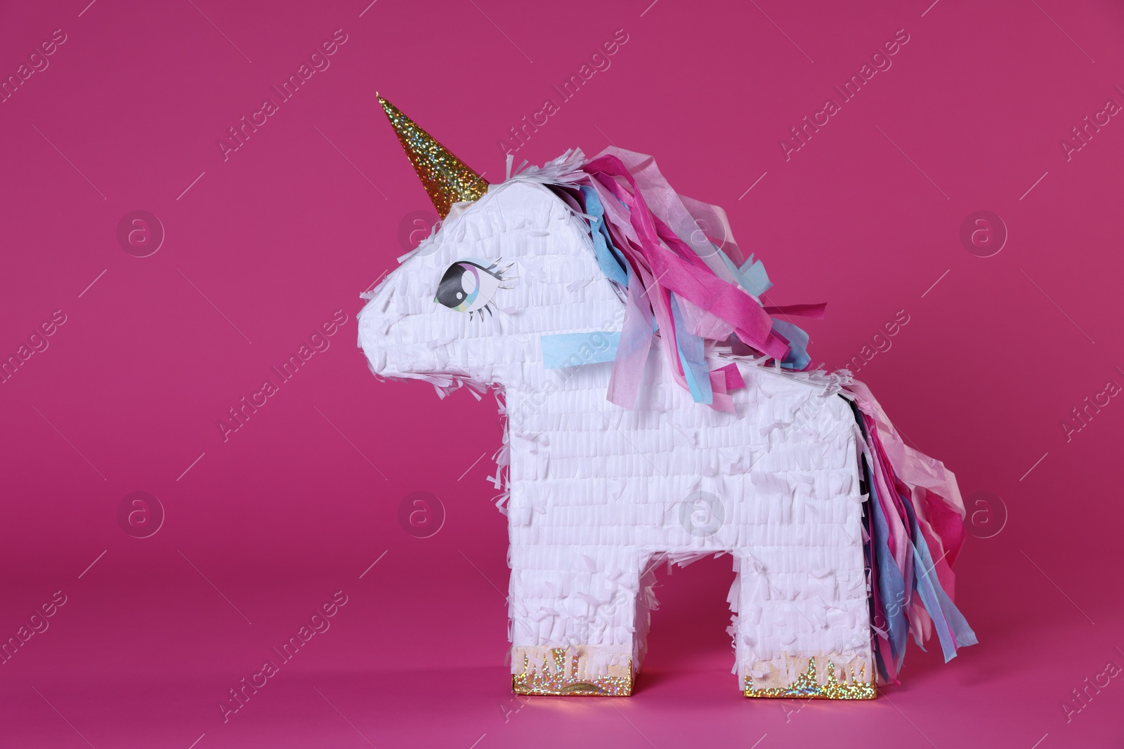 Photo of Unicorn shaped pinata on bright pink background