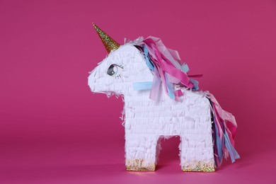 Photo of Unicorn shaped pinata on bright pink background