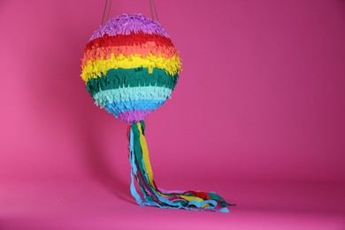 Photo of Colorful pinata on bright pink background, space for text