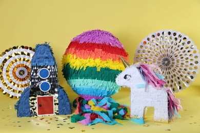 Photo of Different pinatas and party decor on yellow background