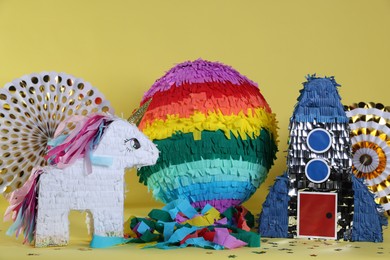 Photo of Different pinatas and party decor on yellow background