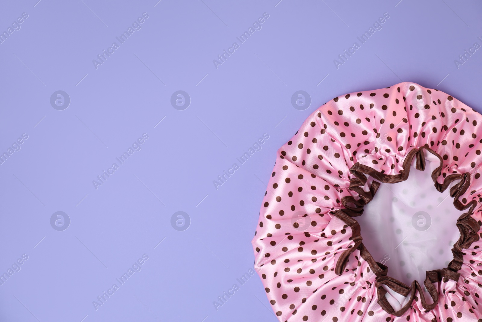 Photo of One shower cap on lilac background, top view. Space for text