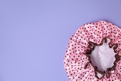 Photo of One shower cap on lilac background, top view. Space for text