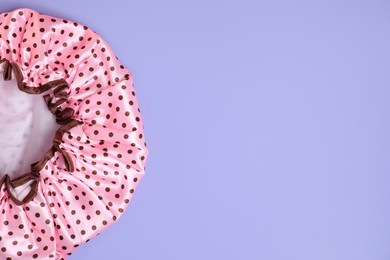 Photo of One shower cap on lilac background, top view. Space for text