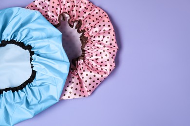 Photo of Two shower caps on lilac background, top view. Space for text