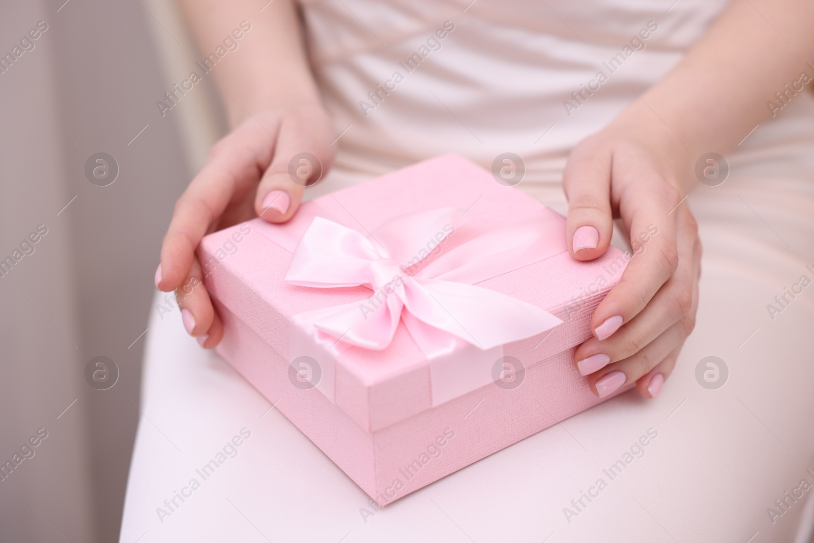 Photo of Bride with beautiful wedding gift indoors, closeup