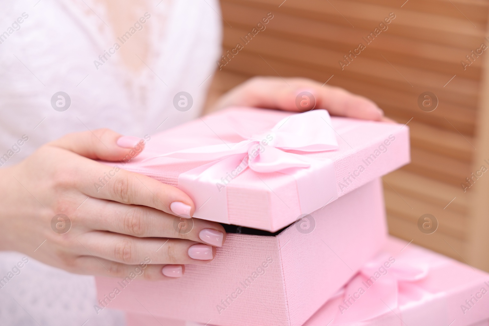 Photo of Bride opening beautiful wedding gift indoors, closeup