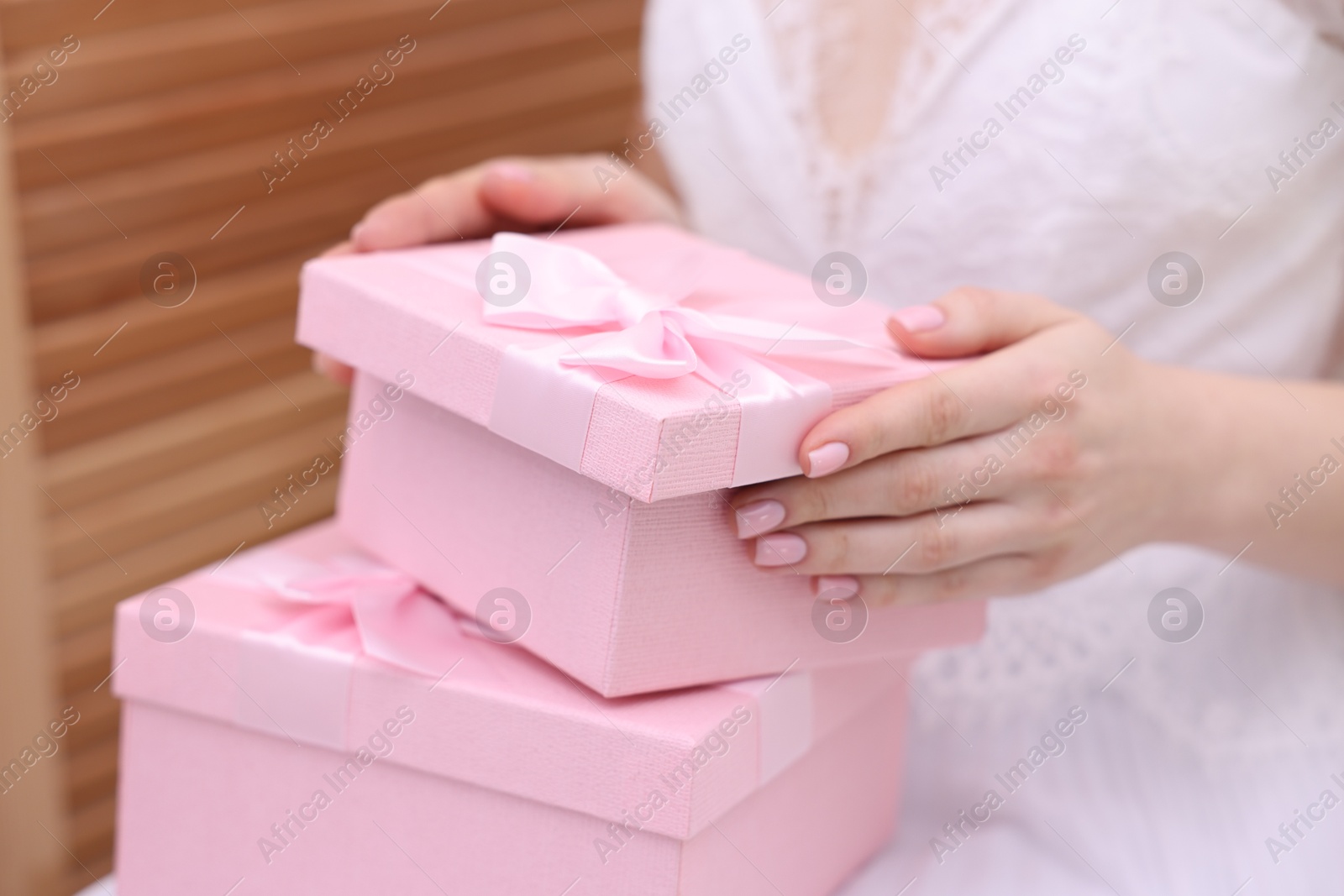 Photo of Bride opening beautiful wedding gift indoors, closeup