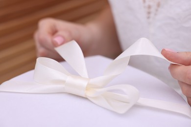 Photo of Bride opening beautiful wedding gift indoors, closeup