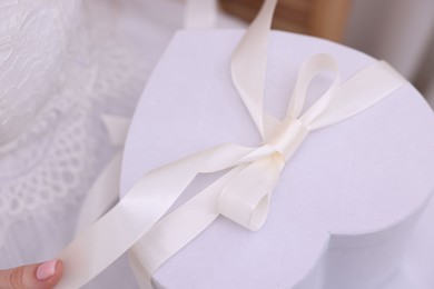 Photo of Bride with beautiful wedding gift indoors, closeup