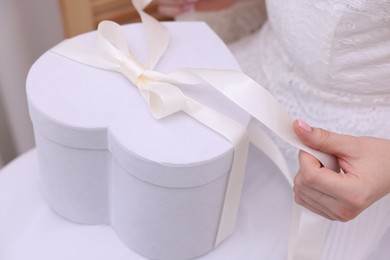 Photo of Bride opening beautiful wedding gift indoors, closeup