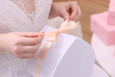 Photo of Bride opening beautiful wedding gift indoors, closeup