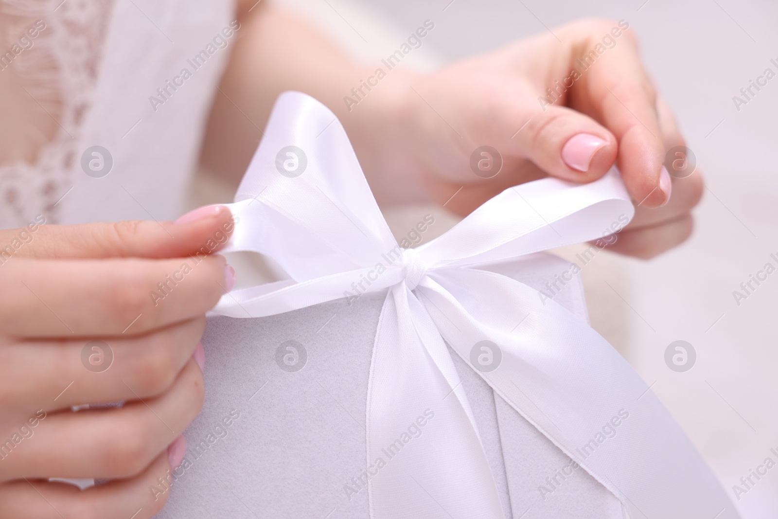 Photo of Bride opening beautiful wedding gift indoors, closeup