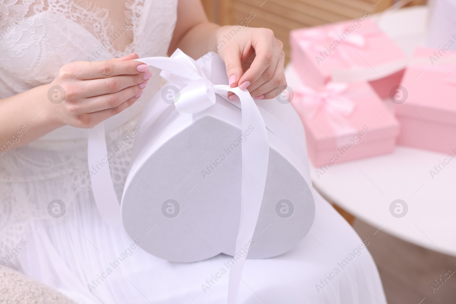 Photo of Bride opening beautiful wedding gift indoors, closeup. Space for text