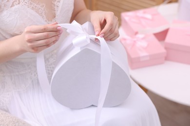 Photo of Bride opening beautiful wedding gift indoors, closeup. Space for text