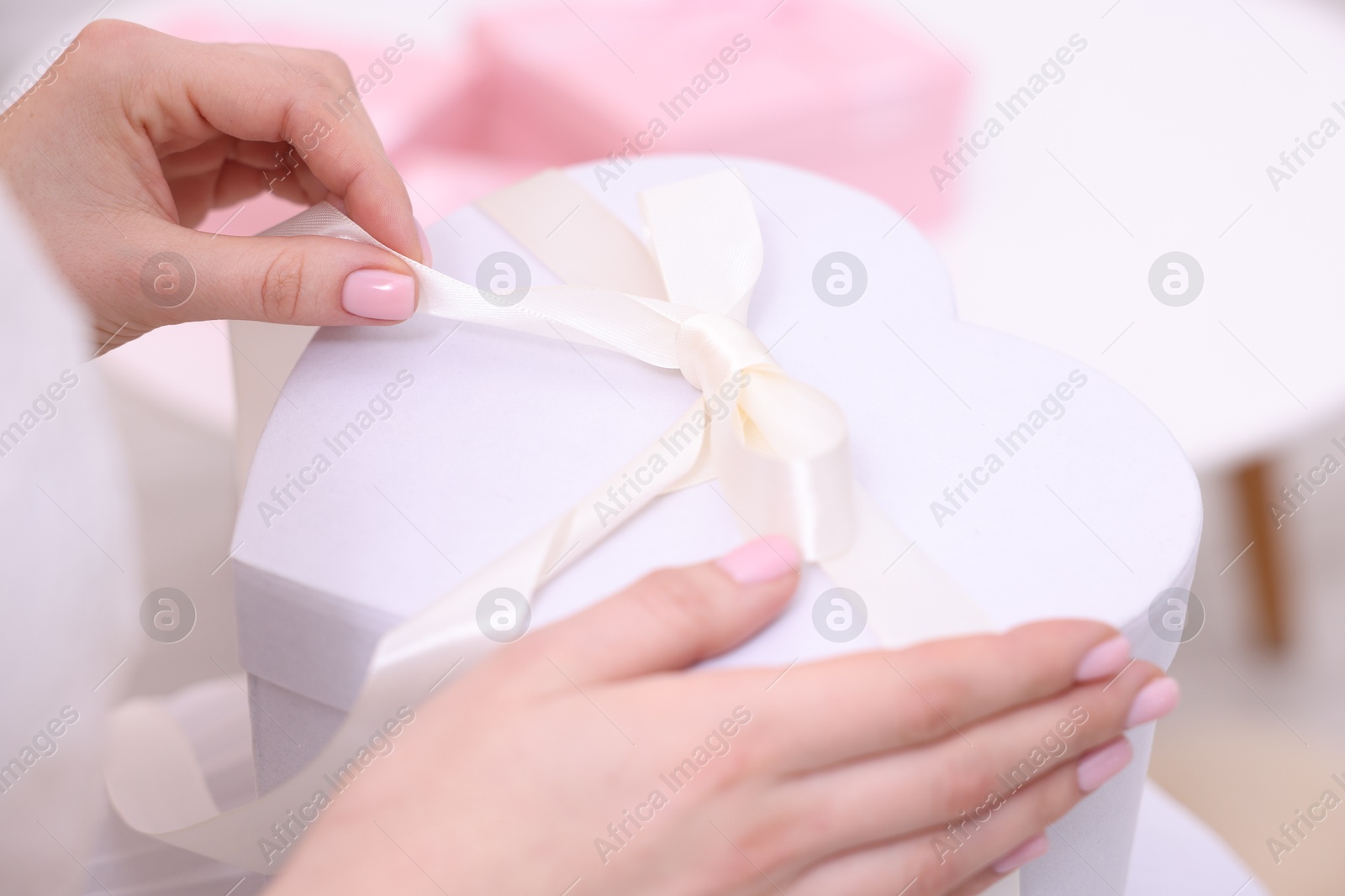 Photo of Bride opening beautiful wedding gift indoors, closeup