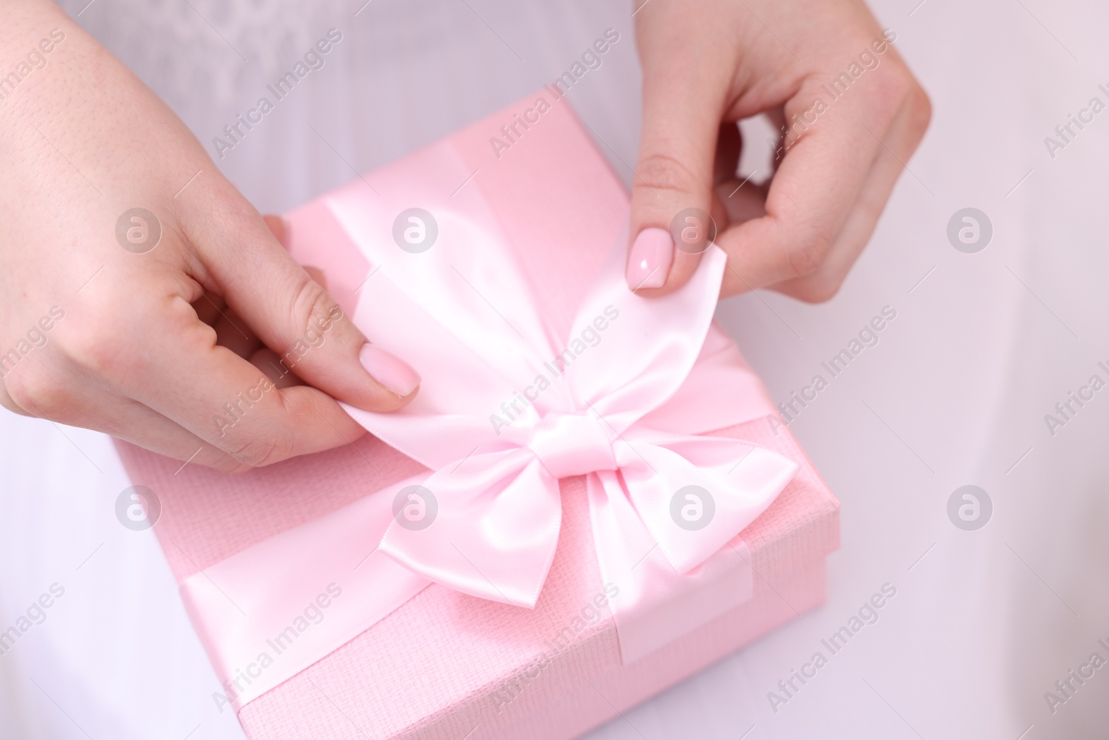 Photo of Bride opening beautiful wedding gift indoors, closeup