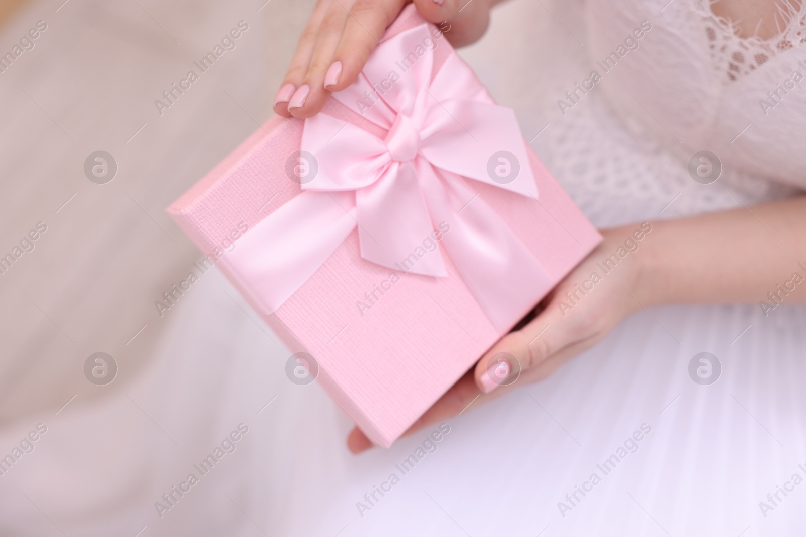 Photo of Bride with beautiful wedding gift indoors, closeup