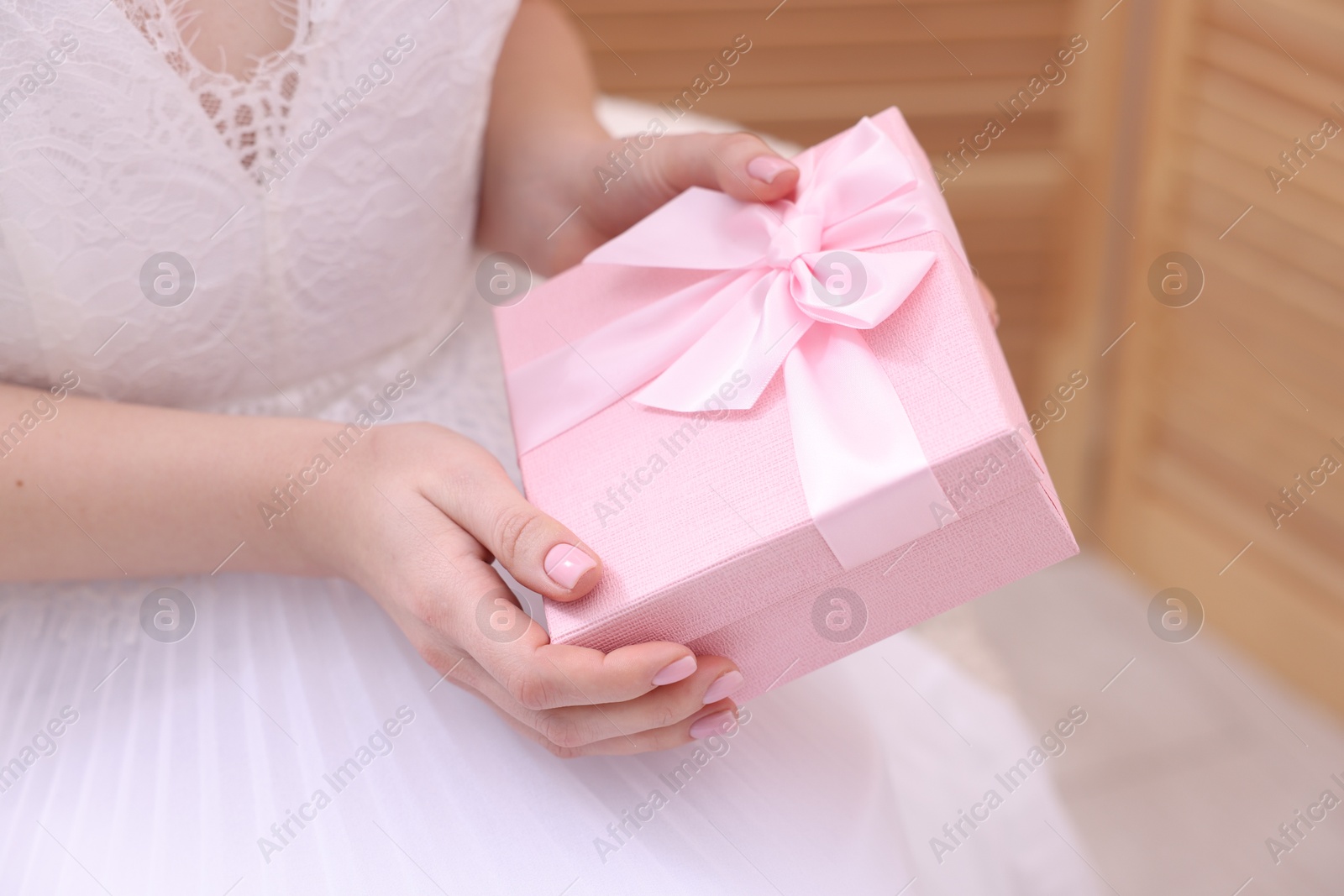 Photo of Bride with beautiful wedding gift indoors, closeup