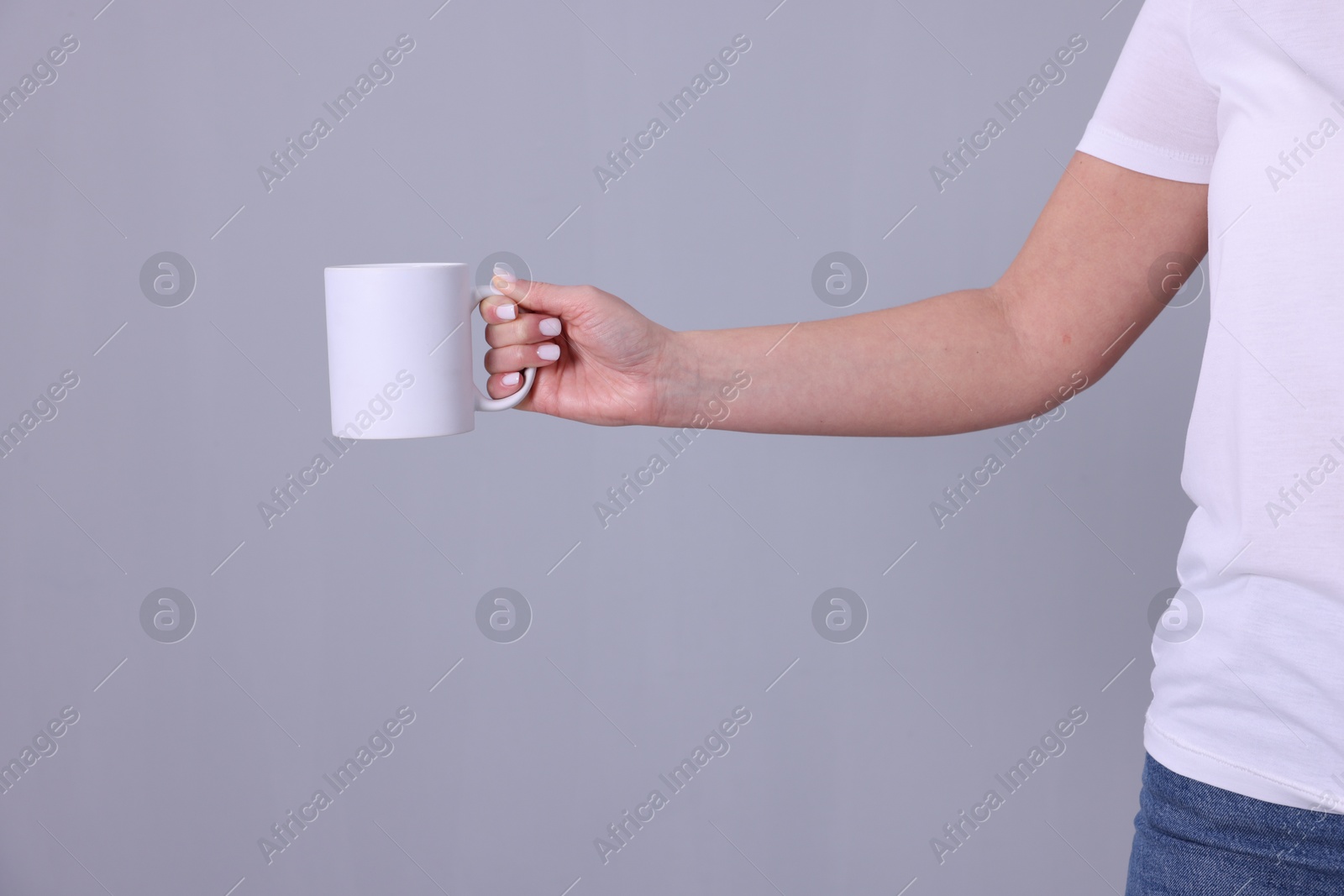 Photo of Woman with blank white cup on grey background, closeup. Mockup for design