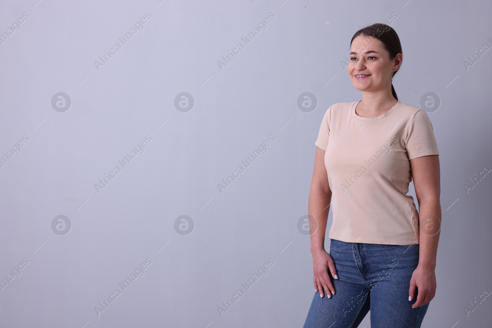 Photo of Woman in beige t-shirt on grey background. Mockup for design