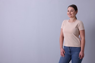 Photo of Woman in beige t-shirt on grey background. Mockup for design