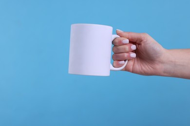 Photo of Woman with blank white cup on light blue background, closeup. Mockup for design