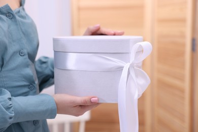 Photo of Woman with beautiful wedding gift indoors, closeup