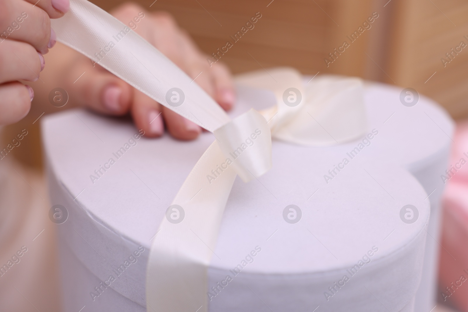 Photo of Bride opening beautiful wedding gift indoors, closeup