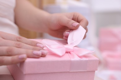 Photo of Bride opening beautiful wedding gift indoors, closeup