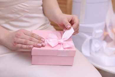 Photo of Bride opening beautiful wedding gift indoors, closeup. Space for text