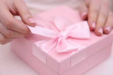 Photo of Bride opening beautiful wedding gift indoors, closeup