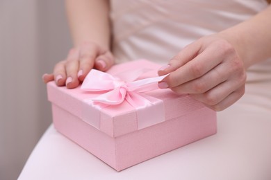 Photo of Bride opening beautiful wedding gift indoors, closeup