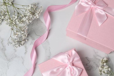 Photo of Beautiful wedding gifts, ribbon and gypsophila flowers on white marble table, flat lay