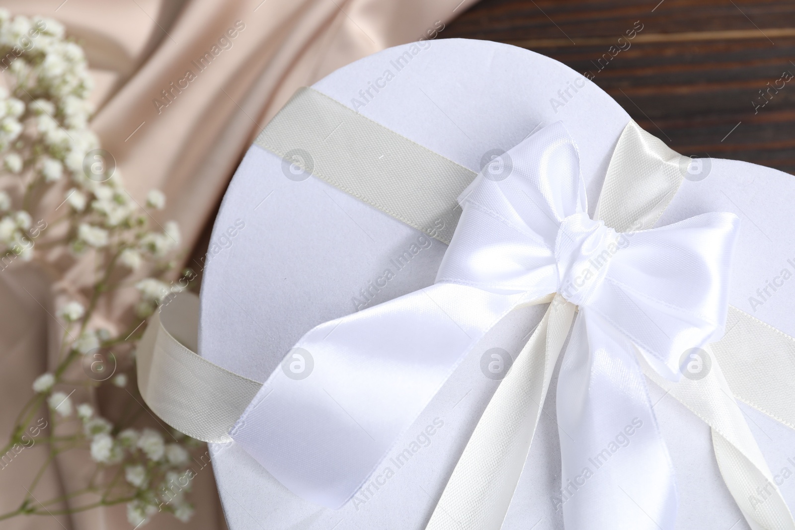 Photo of Beautiful wedding gift, silk fabric and gypsophila flowers on table, above view