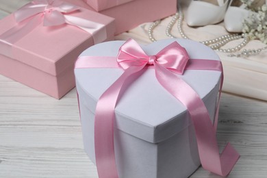 Photo of Beautiful wedding gifts, pearl jewelry, silk fabric, bridal shoes and gypsophila flowers on light wooden table, closeup