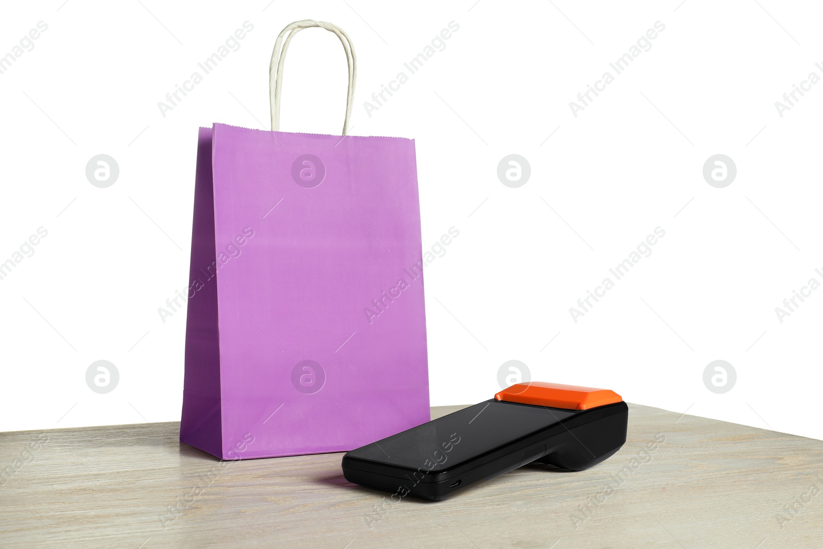 Photo of Payment terminal and shopping bag on wooden table against white background