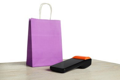 Photo of Payment terminal and shopping bag on wooden table against white background