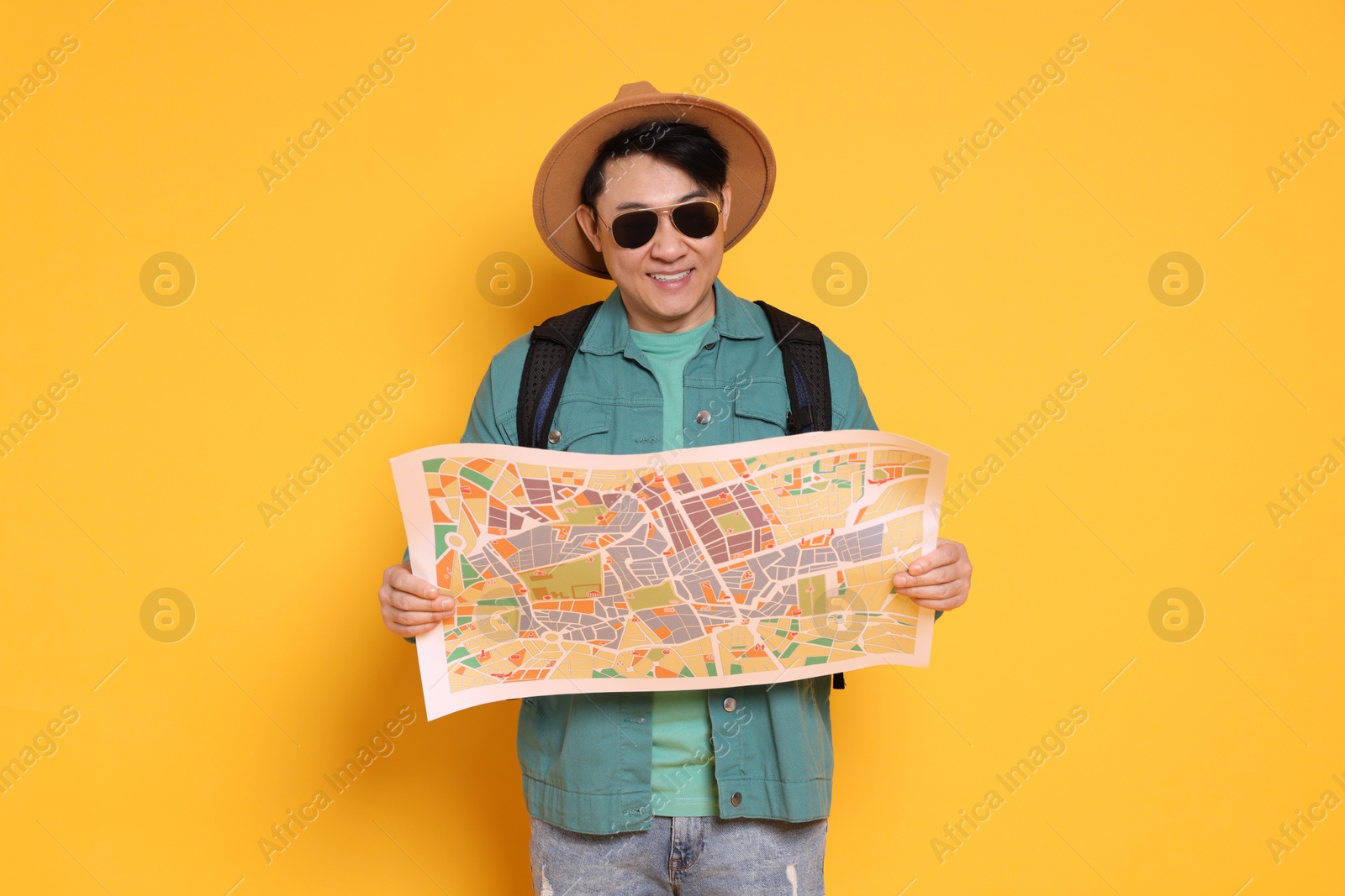 Photo of Traveller with map and backpack on yellow background