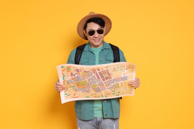 Photo of Traveller with map and backpack on yellow background