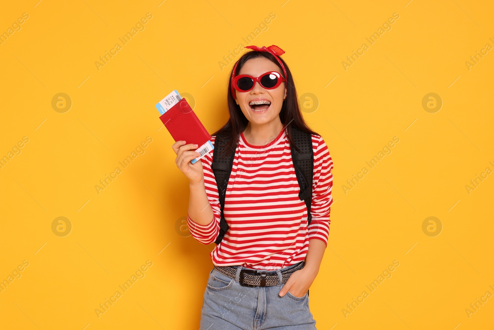 Photo of HAppy traveller with passport on yellow background