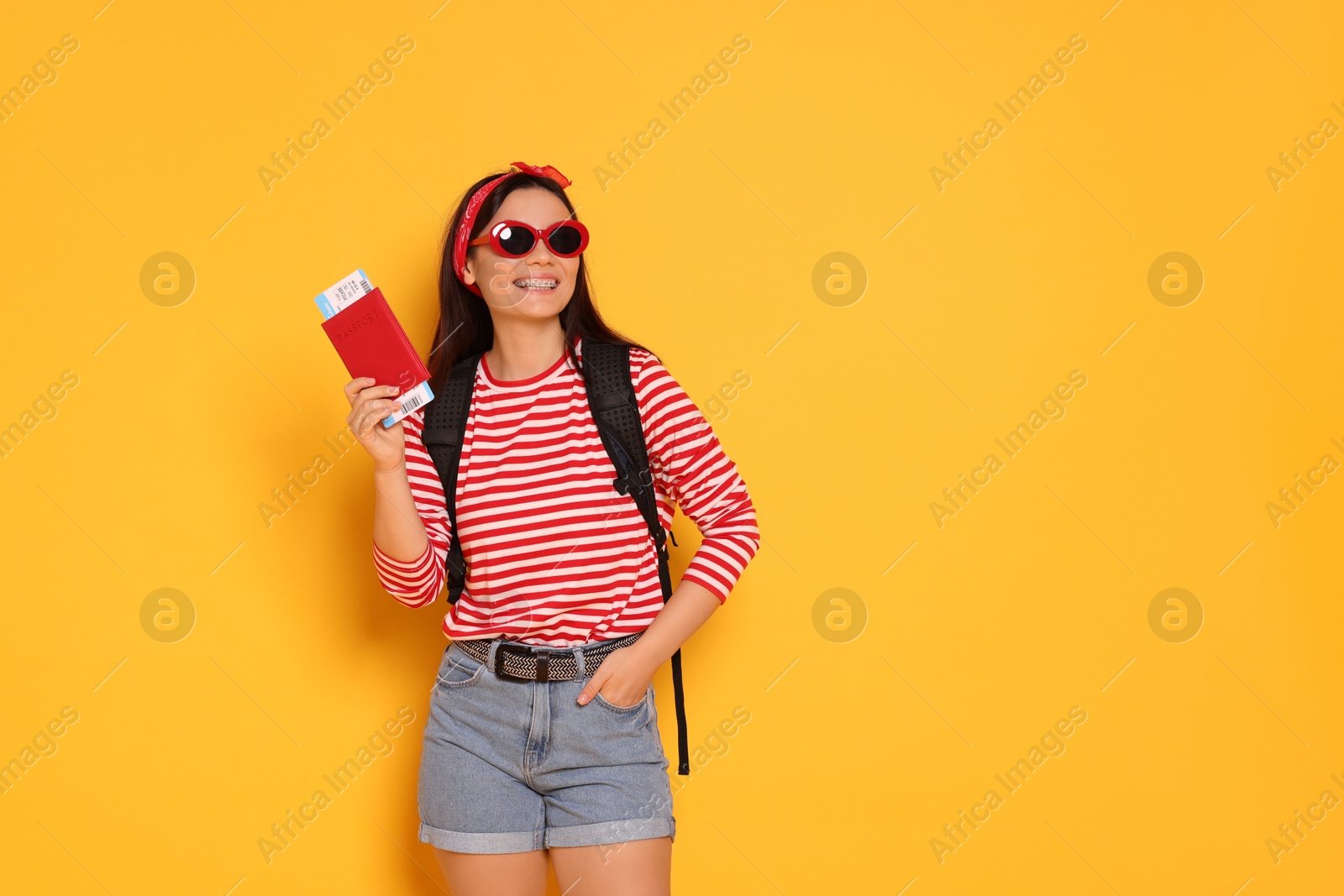 Photo of HAppy traveller with passport on yellow background. Space for text