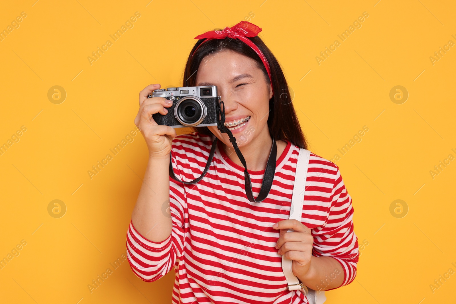 Photo of Happy traveller with camera on yellow background