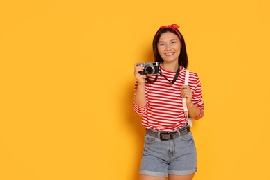 Photo of Happy traveller with camera on yellow background. Space for text