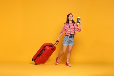 Photo of Happy traveller with passport and suitcase on yellow background