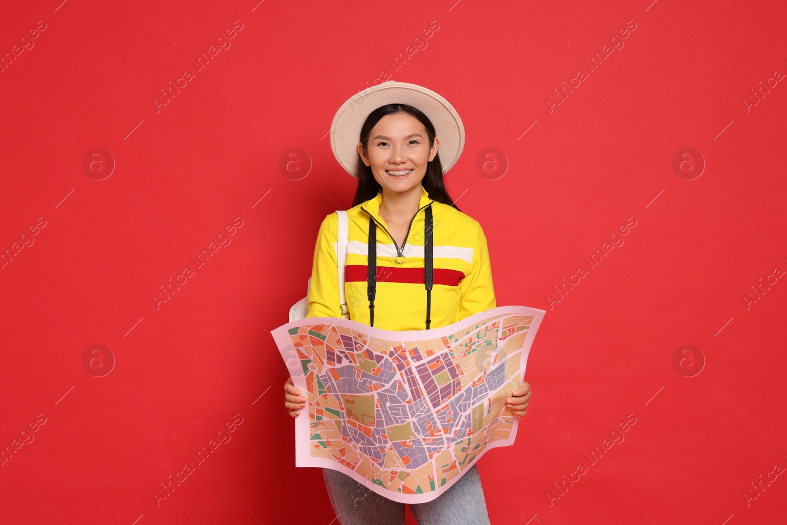 Photo of Happy traveller with map on red background